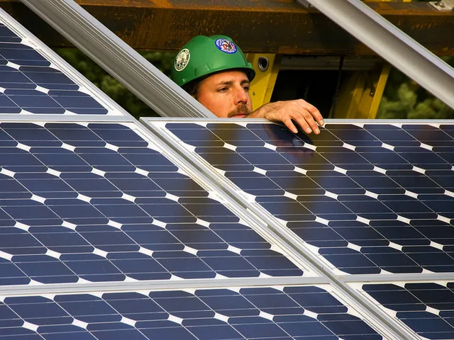 Energetikus szakember védősisakban napelemes panelt rögzít a tetőszerkezeten