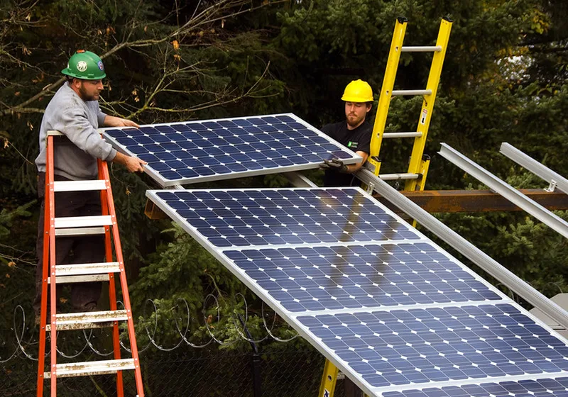 Két létesítmény energetikus szakember napelemes rendszert telepít létrán állva